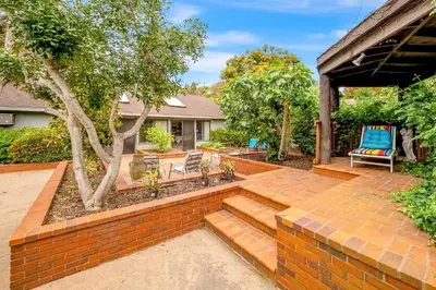 a yard with a brick retaining wall and a patio at Sunny Dreams Home in San Diego