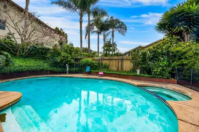 a swimming pool in a yard with palm trees at Sunny Dreams Home in San Diego