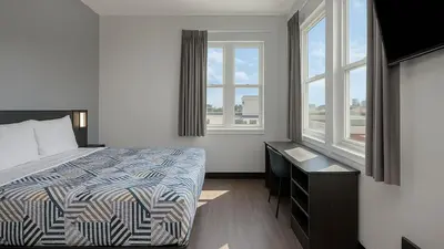 a bedroom with a bed and a desk and windows at Motel 6-San Diego, CA - Downtown in San Diego