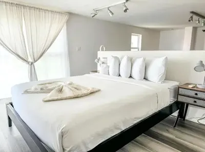 a white bedroom with a large bed with white pillows at Little Italy Modern Lofts in San Diego