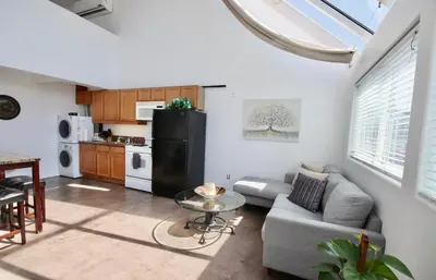 a living room with a couch and a black refrigerator at Little Italy Modern Lofts in San Diego