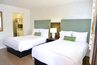 two beds in a hotel room with white sheets at Crown City Inn Coronado in San Diego