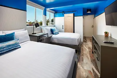 a hotel room with two beds and a desk at Pacific View Inn in San Diego