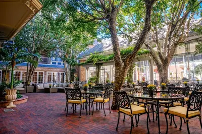 an outdoor patio with tables and chairs and trees at Horton Grand Hotel in San Diego