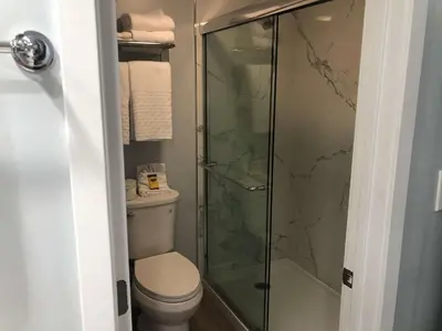 a bathroom with a toilet and a glass shower at Best Western Plus Dana Point Inn-by-the-Sea in Dana Point