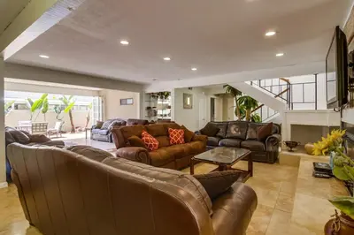 a living room with leather furniture and a staircase at PACIFIC BEACH MANSION in San Diego