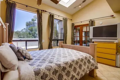 a bedroom with a large bed and a flat screen tv at PACIFIC BEACH MANSION in San Diego