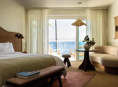 a hotel room with a bed and a couch and a window at Casa Loma Beach Hotel in Laguna Beach