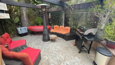a patio with a grill and orange chairs and a table at Kaza Kokos in Oceanside