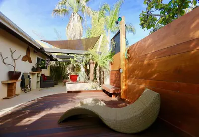 a wicker bench sitting on a deck with a fence at Kaza Kokos in Oceanside