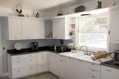 a kitchen with white cabinets and a sink and a window at Apple Tree Inn in Julian