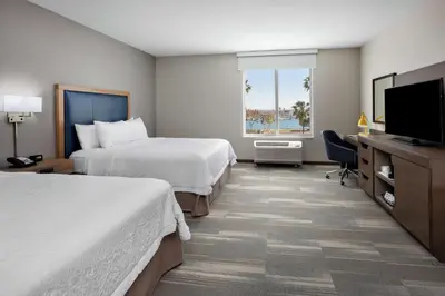 a hotel room with two beds and a flat screen tv at Hampton Inn & Suites San Diego Airport Liberty Station in San Diego