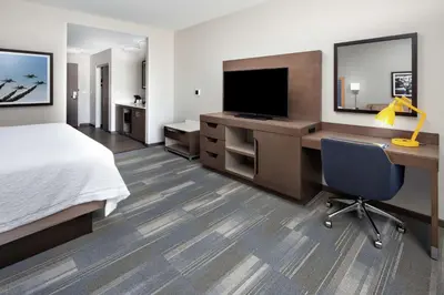 a hotel room with a bed and a desk with a television at Hampton Inn & Suites San Diego Airport Liberty Station in San Diego