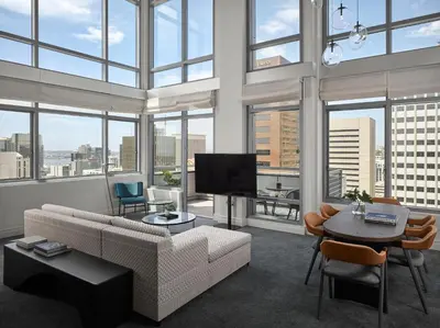 a living room with a couch and a tv and some windows at Alma San Diego Downtown, a Tribute Portfolio Hotel in San Diego