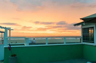 a view of the beach at sunset from the balcony of a house at The Beach Cottages in San Diego