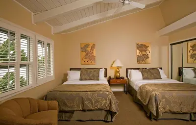 a bedroom with two beds and a chair and windows at Best Western PLUS Island Palms Hotel & Marina in San Diego