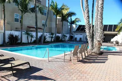 a resort swimming pool with chairs and palm trees at Capri Beach Accommodations at Capri By The Sea in San Diego