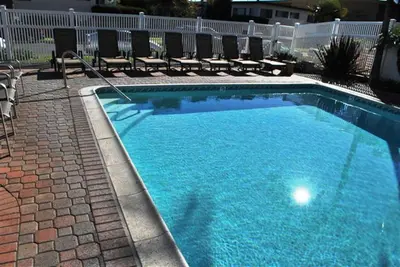 a large blue swimming pool with chairs around it at Capri Beach Accommodations at Capri By The Sea in San Diego