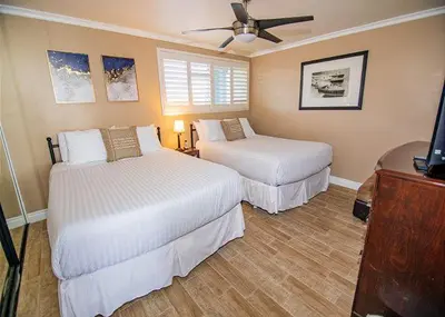 a bedroom with two beds and a ceiling fan at Capri Beach Accommodations at Capri By The Sea in San Diego
