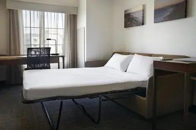 a bed in a hotel room with a desk and a chair at Residence Inn San Diego Del Mar in San Diego