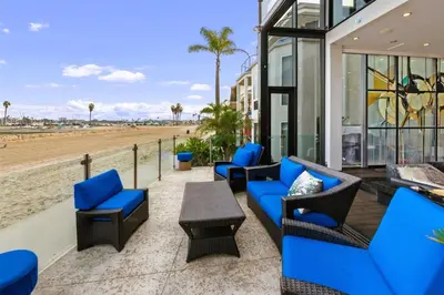 a patio with blue chairs and tables and a beach at 105-Sleekretreat in San Diego