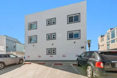a white building with two cars parked in a parking lot at 102-Luxury2 in San Diego