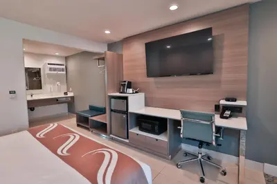 a hotel room with a desk and a tv on a wall at Rodeway Inn San Clemente in San Clemente
