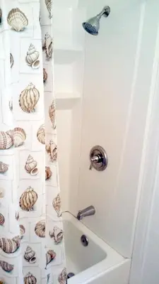 a bathroom with a shower with shells on the wall at 25 Steps to the Beach in Newport Beach