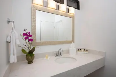 a bathroom sink with a mirror and a vase of flowers at La Jolla Shores Hotel in San Diego