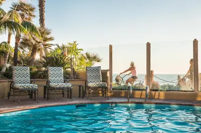a woman riding a bike next to a swimming pool at Pacific Terrace Hotel in San Diego