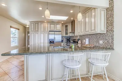 a kitchen with white cabinets and two bar stools at Ocean Beach Cliffs Sanctuary Oceanfront in San Diego