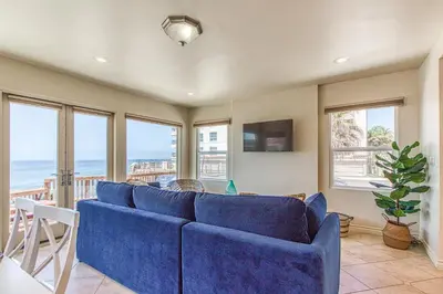 a living room with a blue couch and windows at Ocean Beach Cliffs Sanctuary Oceanfront in San Diego