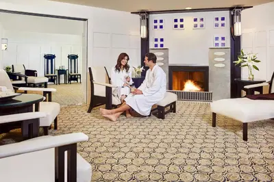 a man and woman sitting in a room with a fireplace at The Lodge at Torrey Pines in San Diego