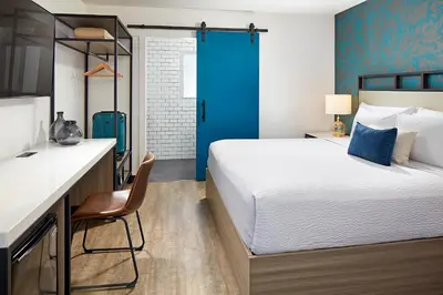 a bedroom with a large bed and a blue door at The Shoal Hotel La Jolla Beach in San Diego