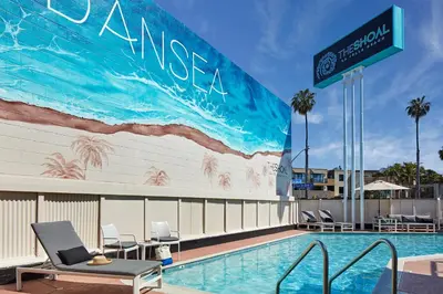 a swimming pool with chairs next to a building with a mural at The Shoal Hotel La Jolla Beach in San Diego
