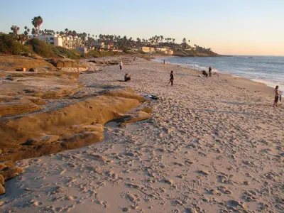 a group of people walking on the beach at The Shoal Hotel La Jolla Beach in San Diego