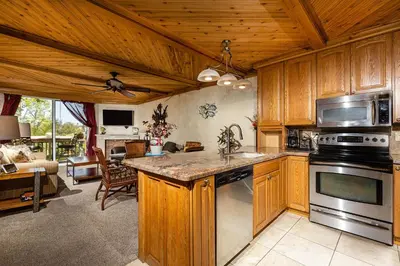 a kitchen with wooden cabinets and a stove top oven at Penthouse Condo w/ Panoramic Ocean Views at Beach Resort in Oceanside