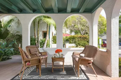 a porch with three chairs and a table with flowers on it at 1906 Lodge in San Diego