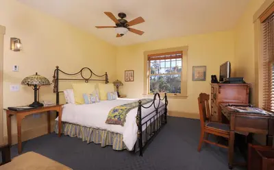 a bedroom with a bed with a ceiling fan and a desk at 1906 Lodge in San Diego