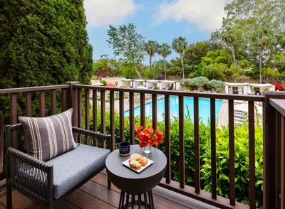 a chair on a deck with a table with food on it at Estancia La Jolla Hotel & Spa in San Diego