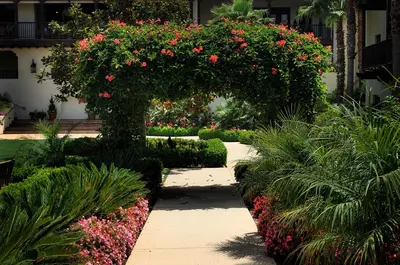 a garden with red flowers and a walkway at Estancia La Jolla Hotel & Spa in San Diego