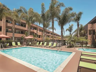 a pool at a hotel with chairs and palm trees at Mission View Inn & Suites San Diego Sea World - Zoo in San Diego