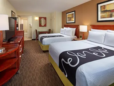 a hotel room with two beds and a flat screen tv at Mission View Inn & Suites San Diego Sea World - Zoo in San Diego