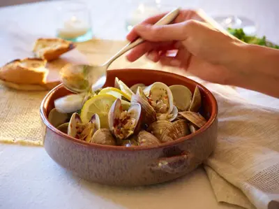 a person holding a spoon in a bowl of clams at San Diego Mission Bay Resort in San Diego