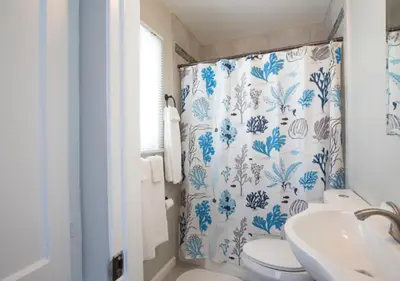 a bathroom with a shower curtain with a toilet and a sink at MB Jamaica FLAT - Steps 2 Mission Beach in San Diego