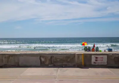a beach with people and an umbrella and the ocean at MB Jamaica FLAT - Steps 2 Mission Beach in San Diego