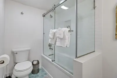 a bathroom with a shower and a toilet and towels at Beachfront feat Private Den SS166 in Solana Beach