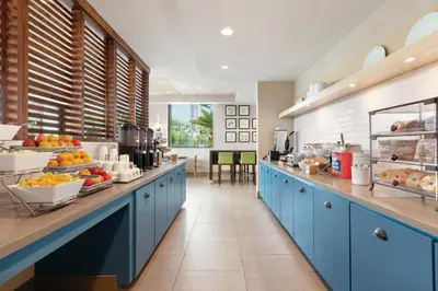 a large kitchen with blue cabinets and fruits on display at Country Inn & Suites by Radisson, San Diego North, CA in Mira Mesa