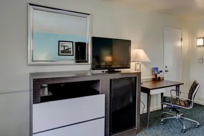 a hotel room with a desk and a flat screen tv at Kings Inn in San Diego