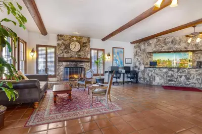 a living room with a fireplace and a stone wall at Best Western Plus Hacienda Hotel Old Town in San Diego